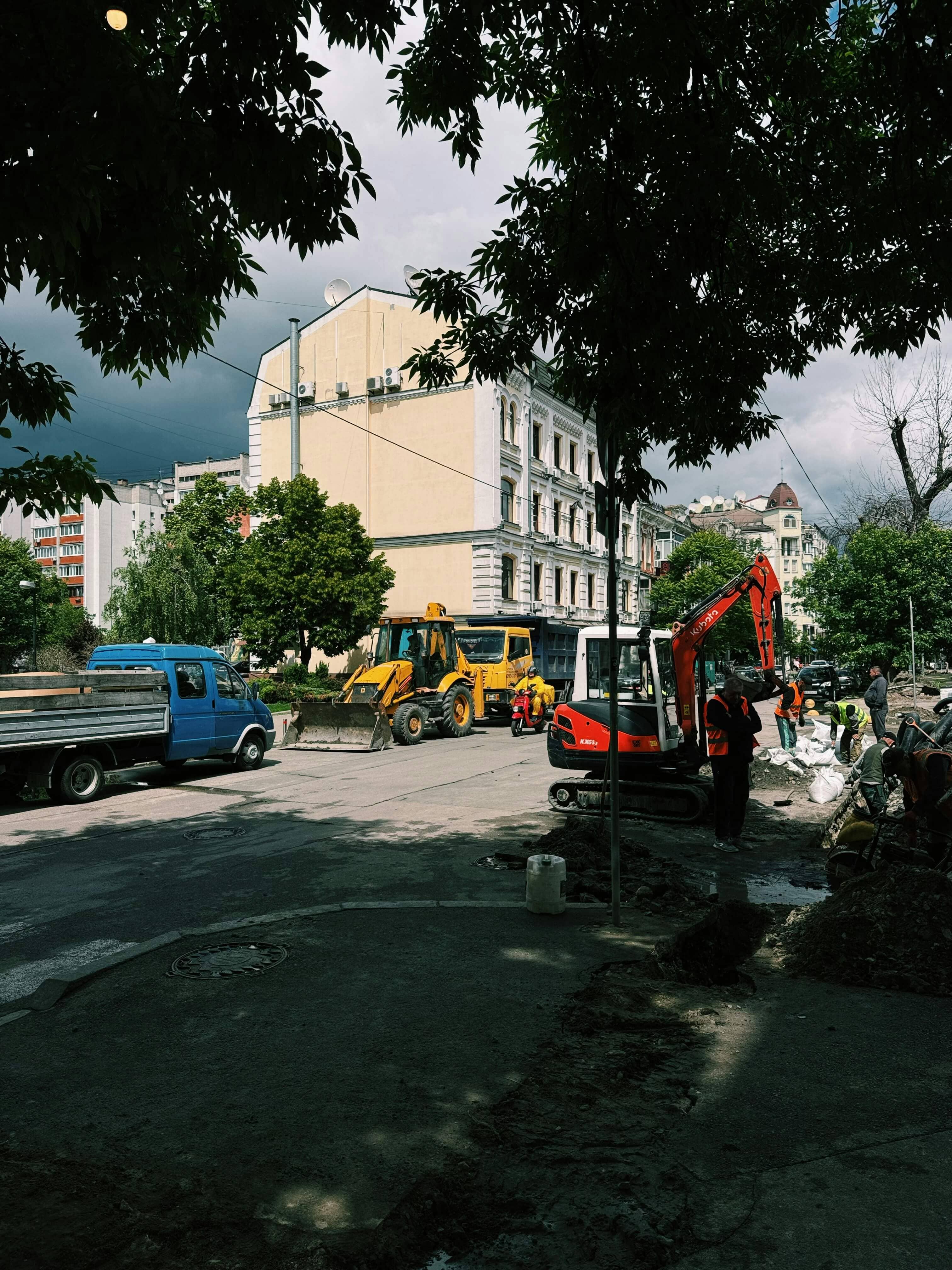 Construction excavator with workers on an active urban job site